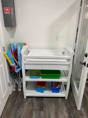 White changing table with storage shelves and colorful bins