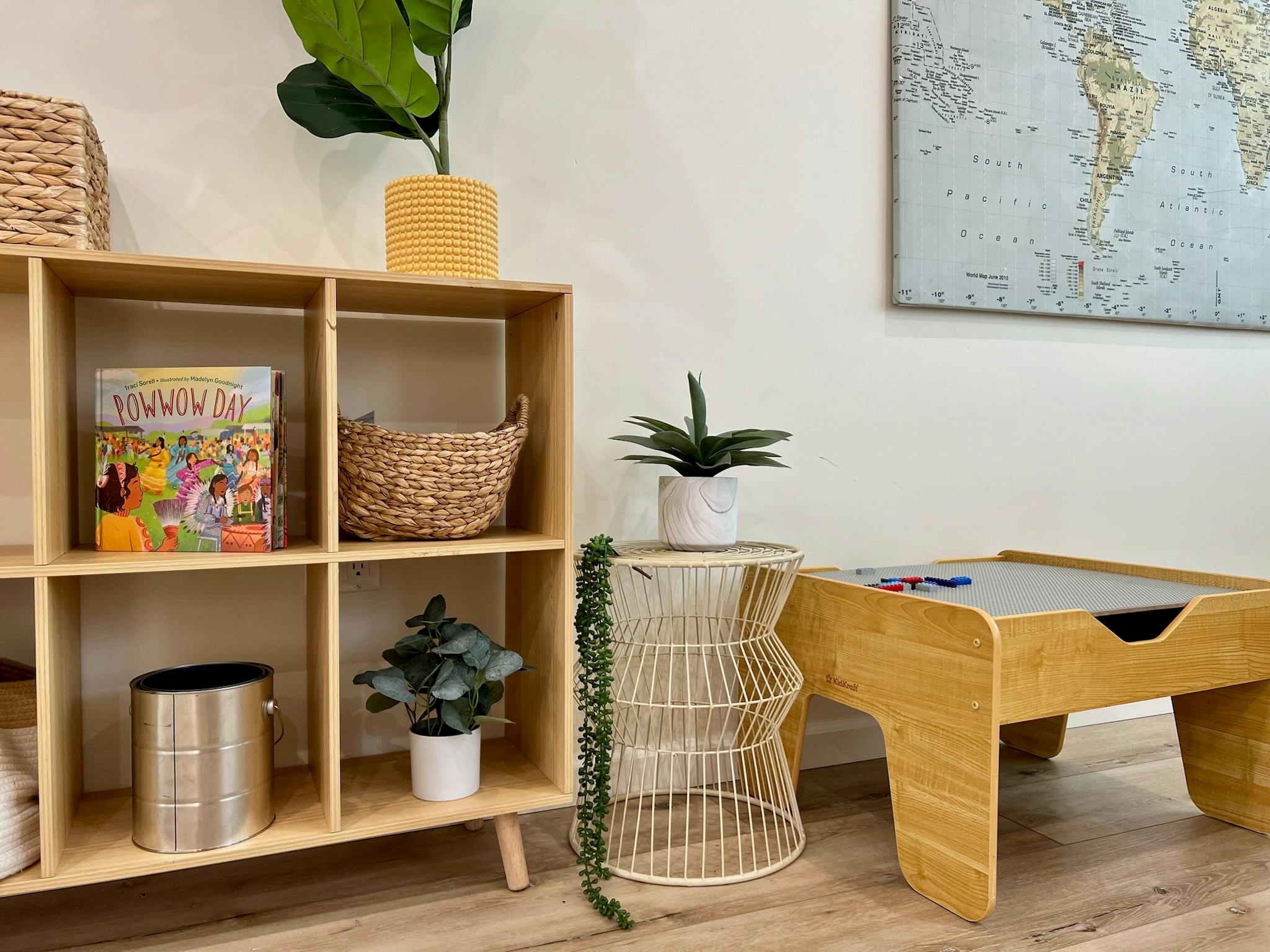 Wooden shelving unit with plants and baskets next to a small wooden table