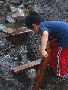 Child looking down at a wooden plank over rocks
