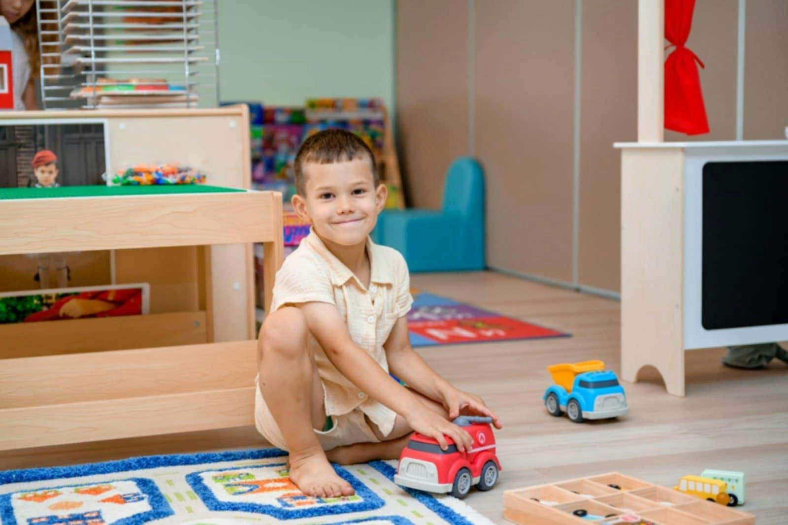 Child playing with a toy truck on a rug in a playroom