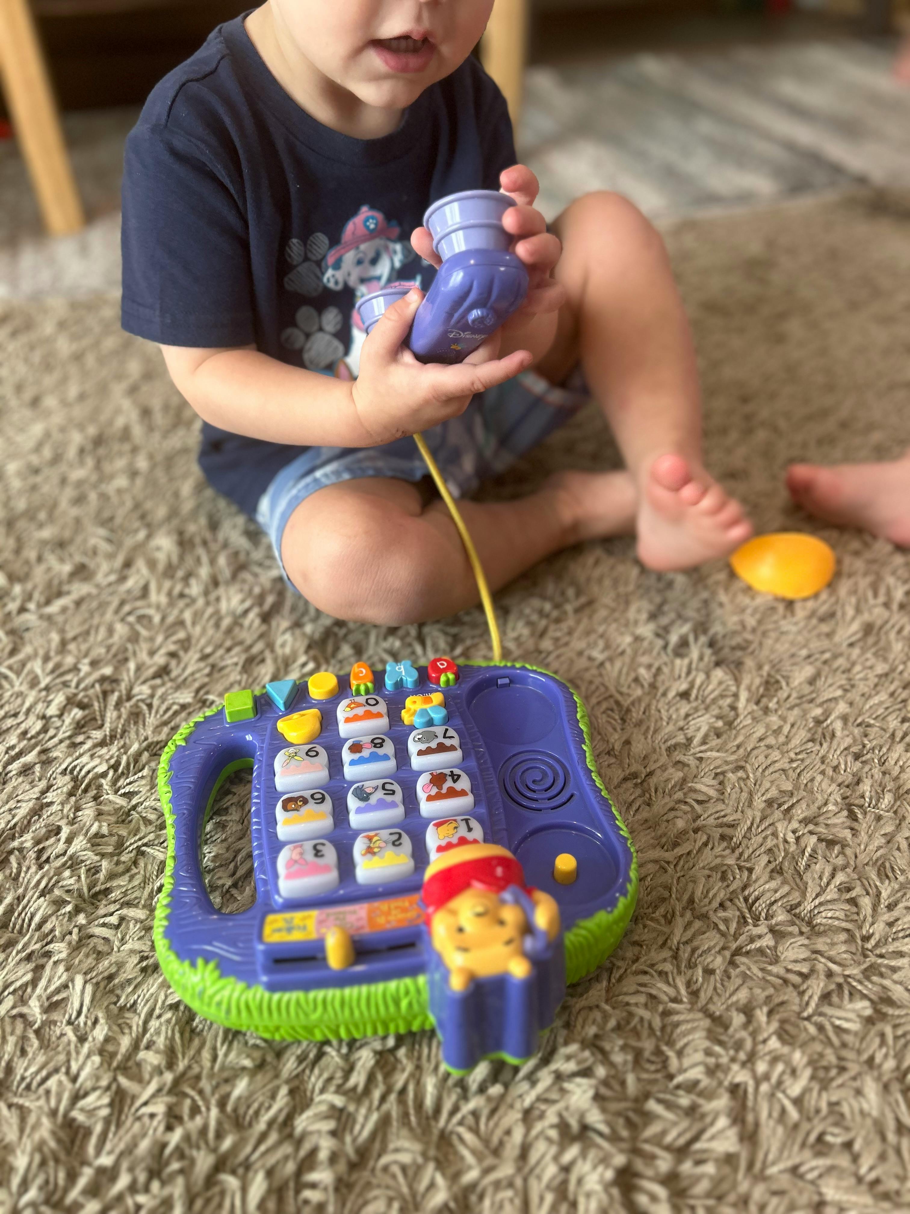 Child playing with a toy phone on a carpet
