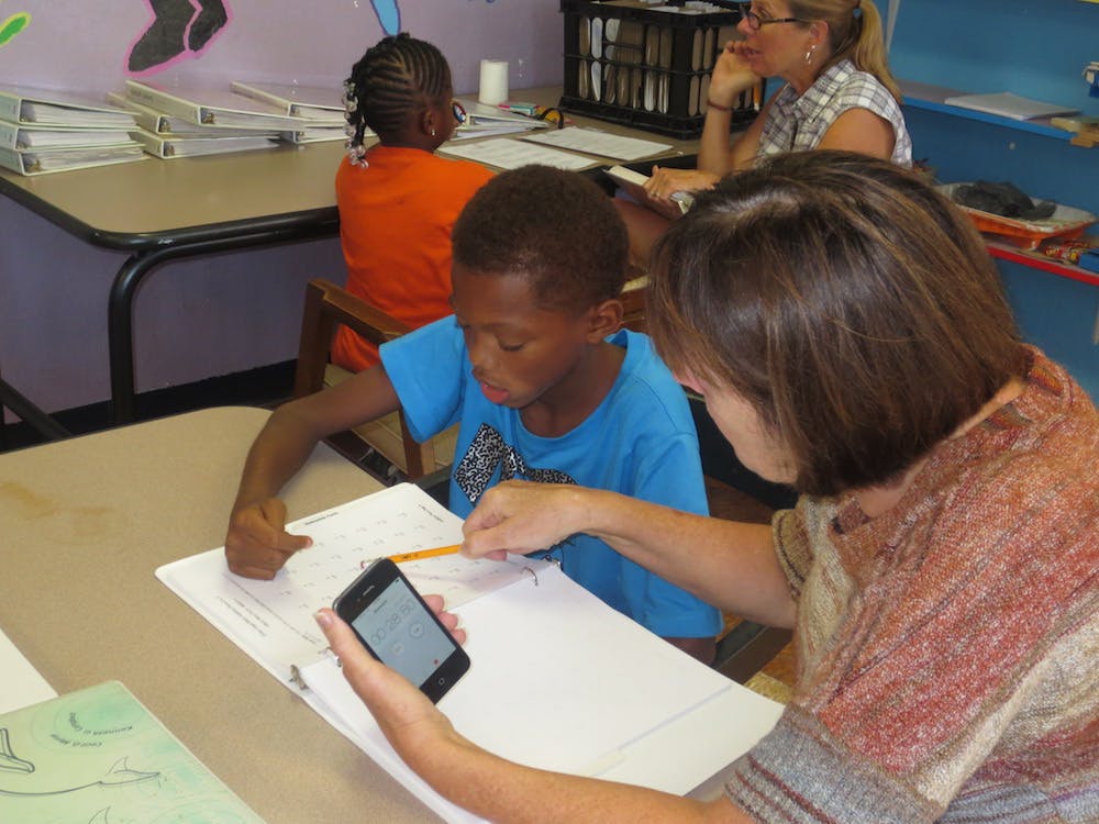 Adult and child looking at paper and phone in a classroom