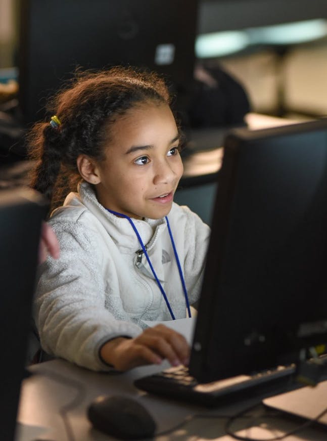 Child looking at a computer screen and typing on a keyboard