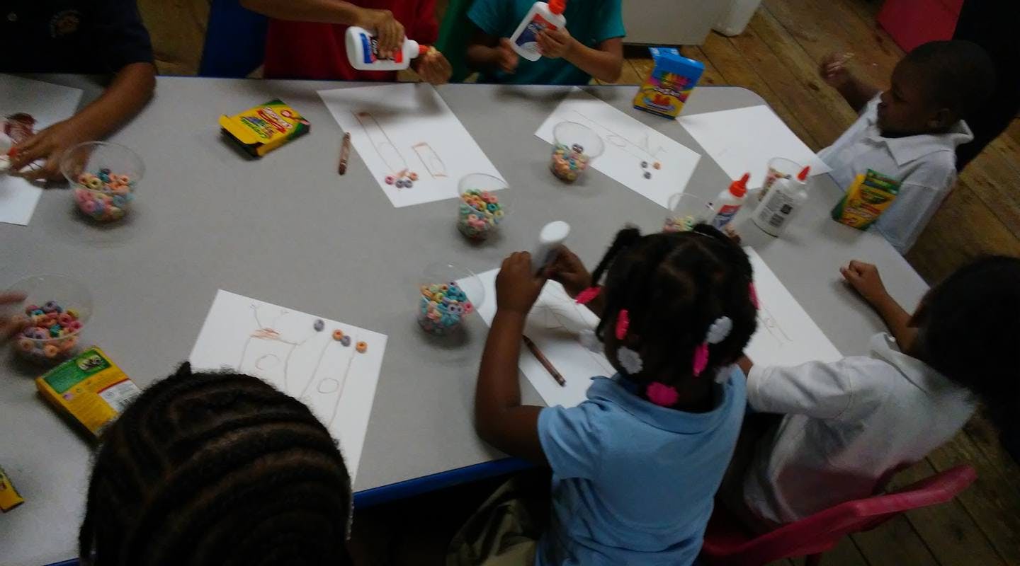 Children at a table doing crafts with arts and crafts