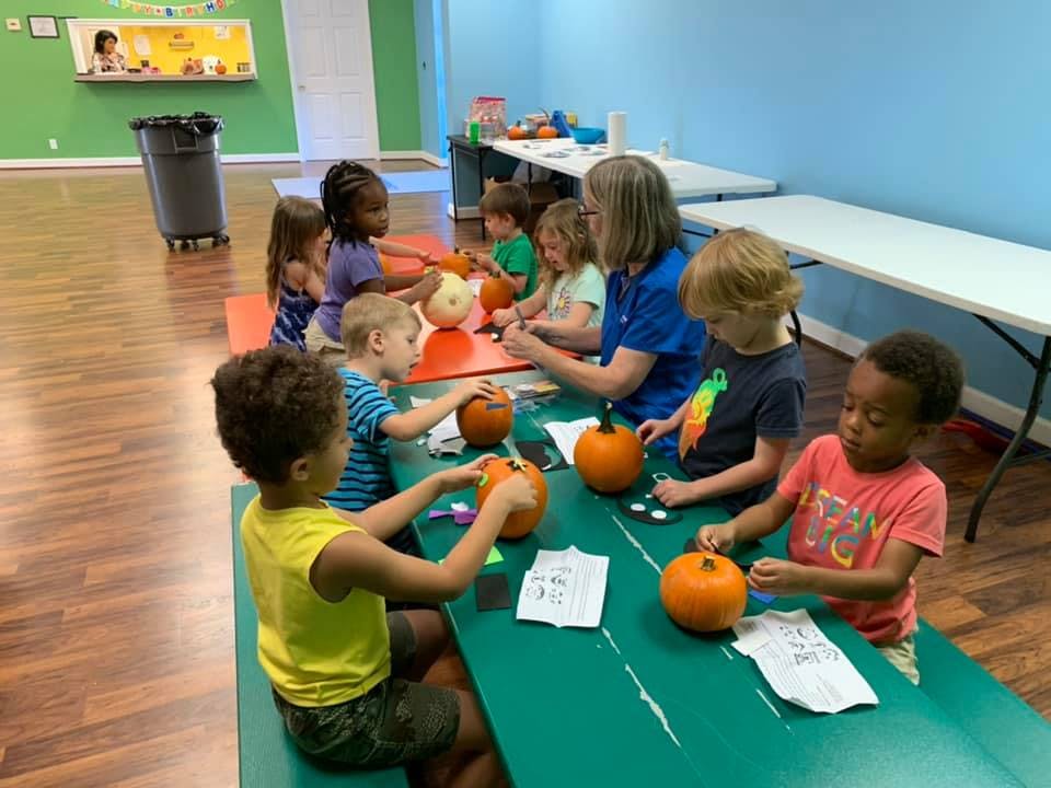 Adult and children decorating pumpkins at a table