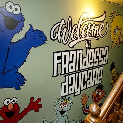 Wall mural with Cookie Monster, Elmo, and text "Welcome to Frandessa Daycare"