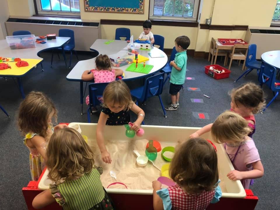 Children playing in a sand table in a classroom