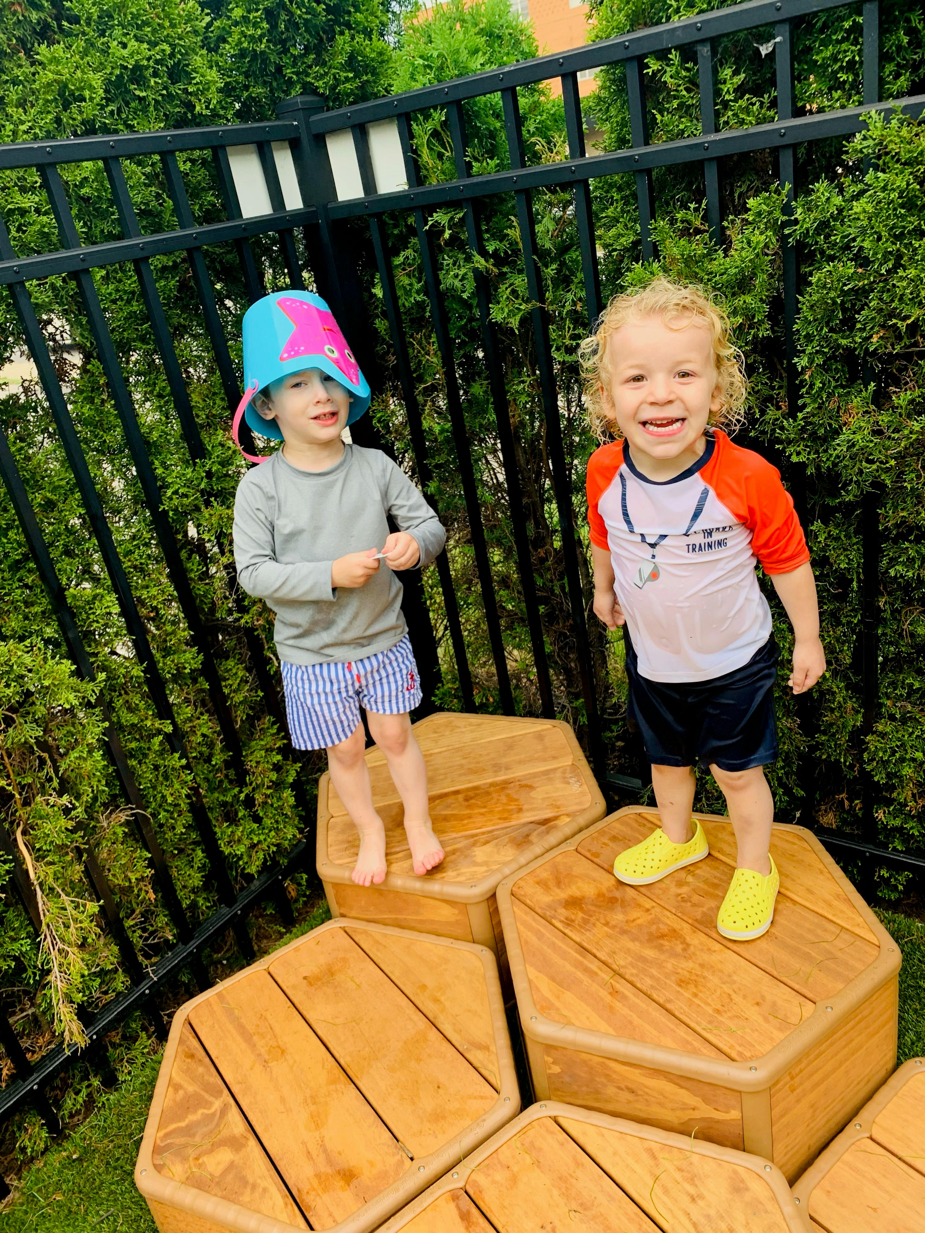 Two children standing on wooden hexagonal blocks outdoors