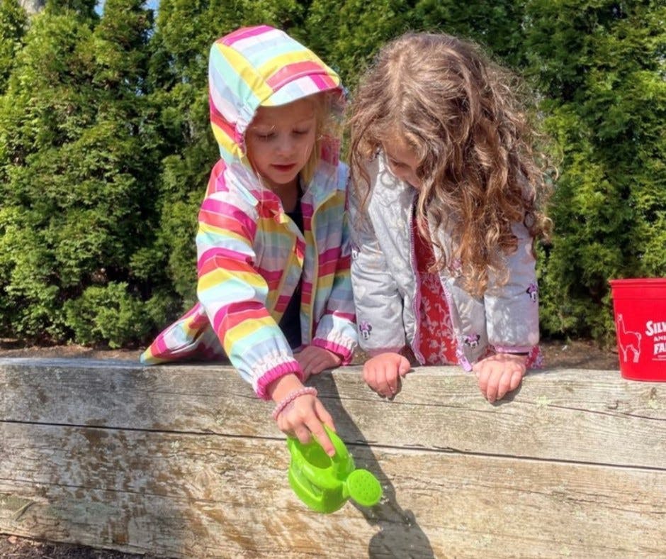 Two children playing with a green watering can
