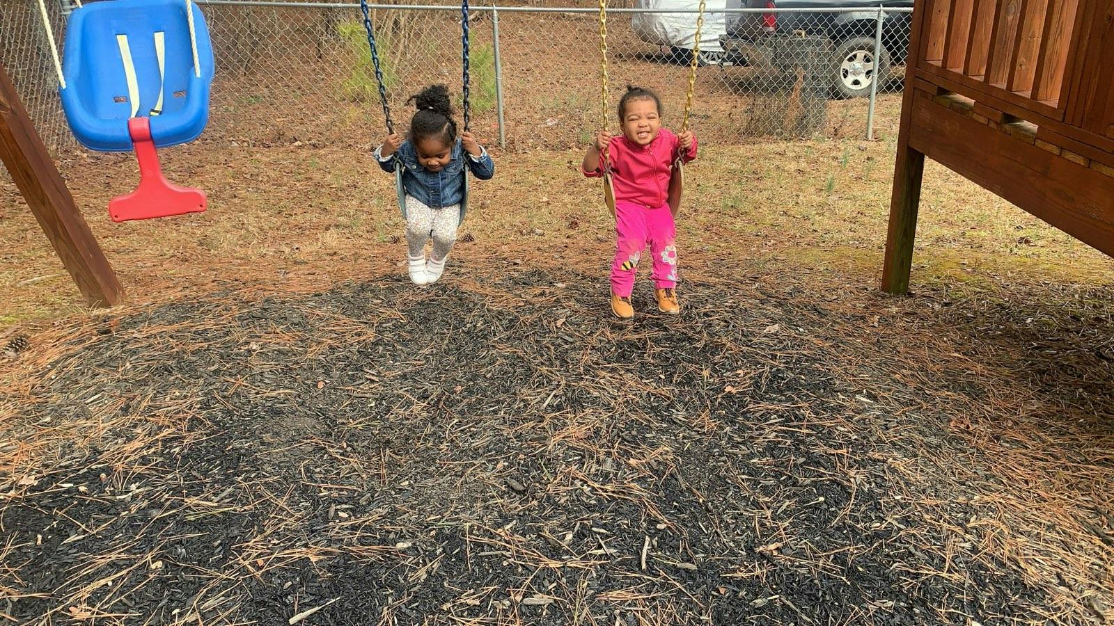 Two children swinging on a backyard playset