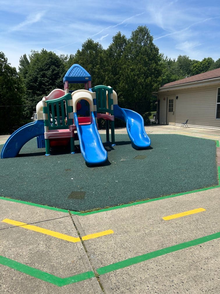 Colorful playground structure with slides on rubberized ground next to a building