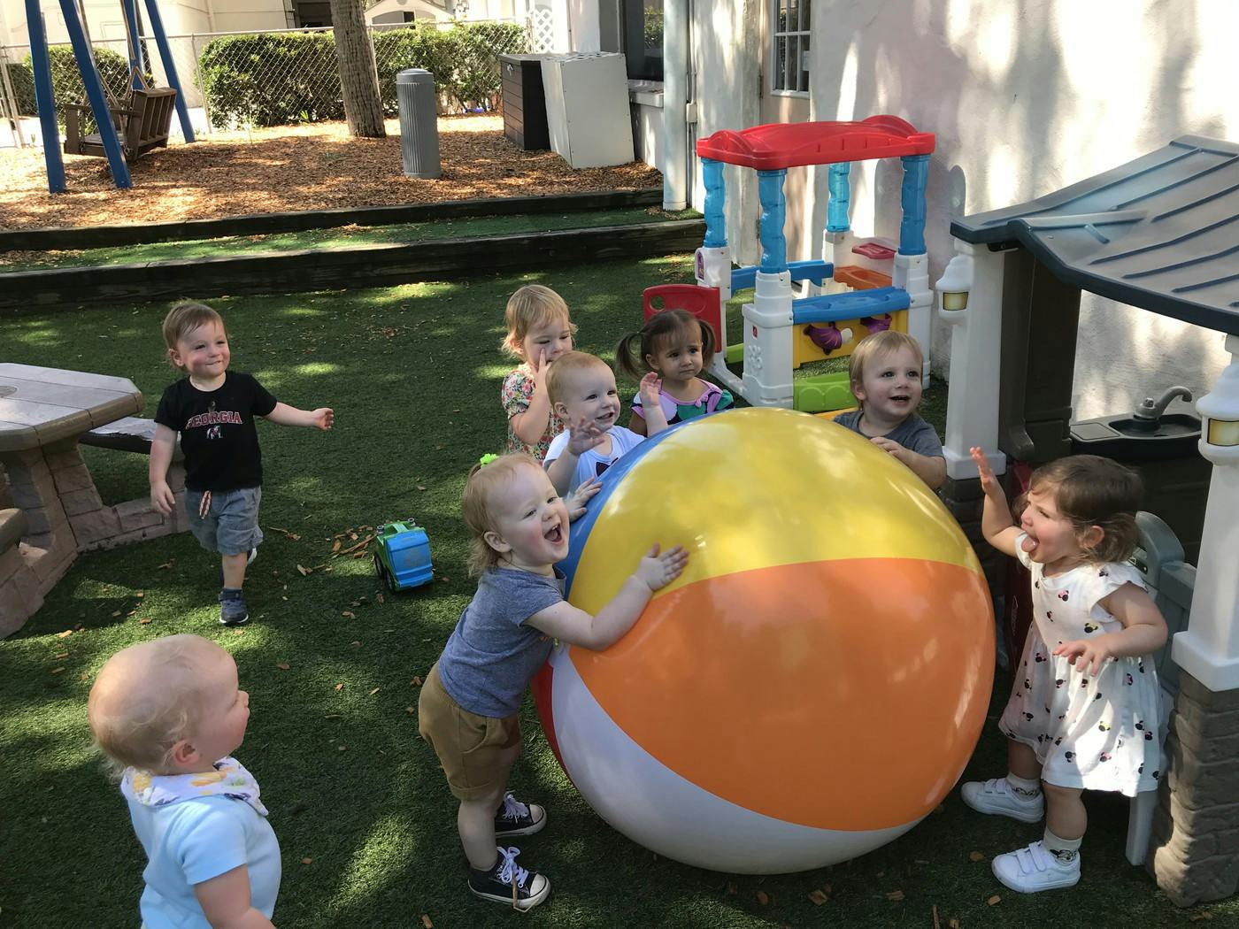 Multiple children playing with a large beach ball outdoors