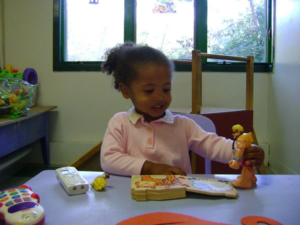Child playing with toys and a book at a table