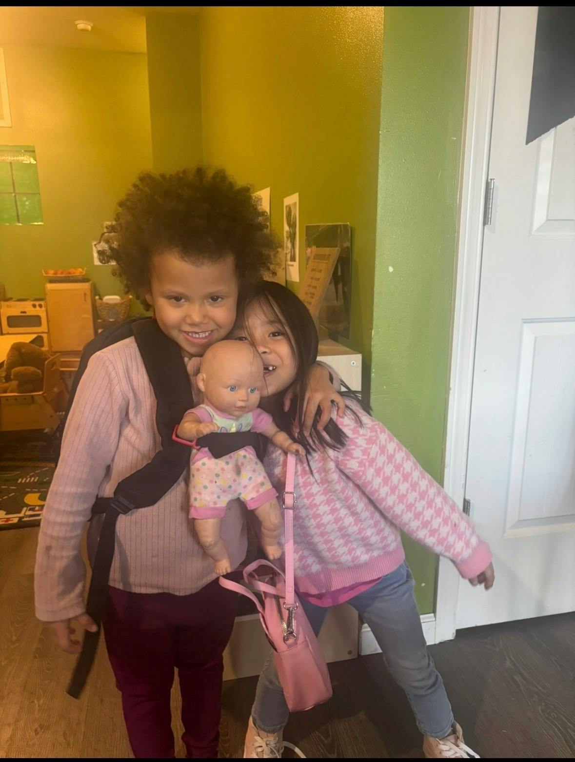 Two children hugging and holding a baby doll indoors