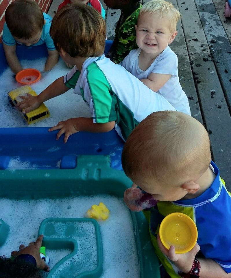 Children playing with toys in a water table with bubbles