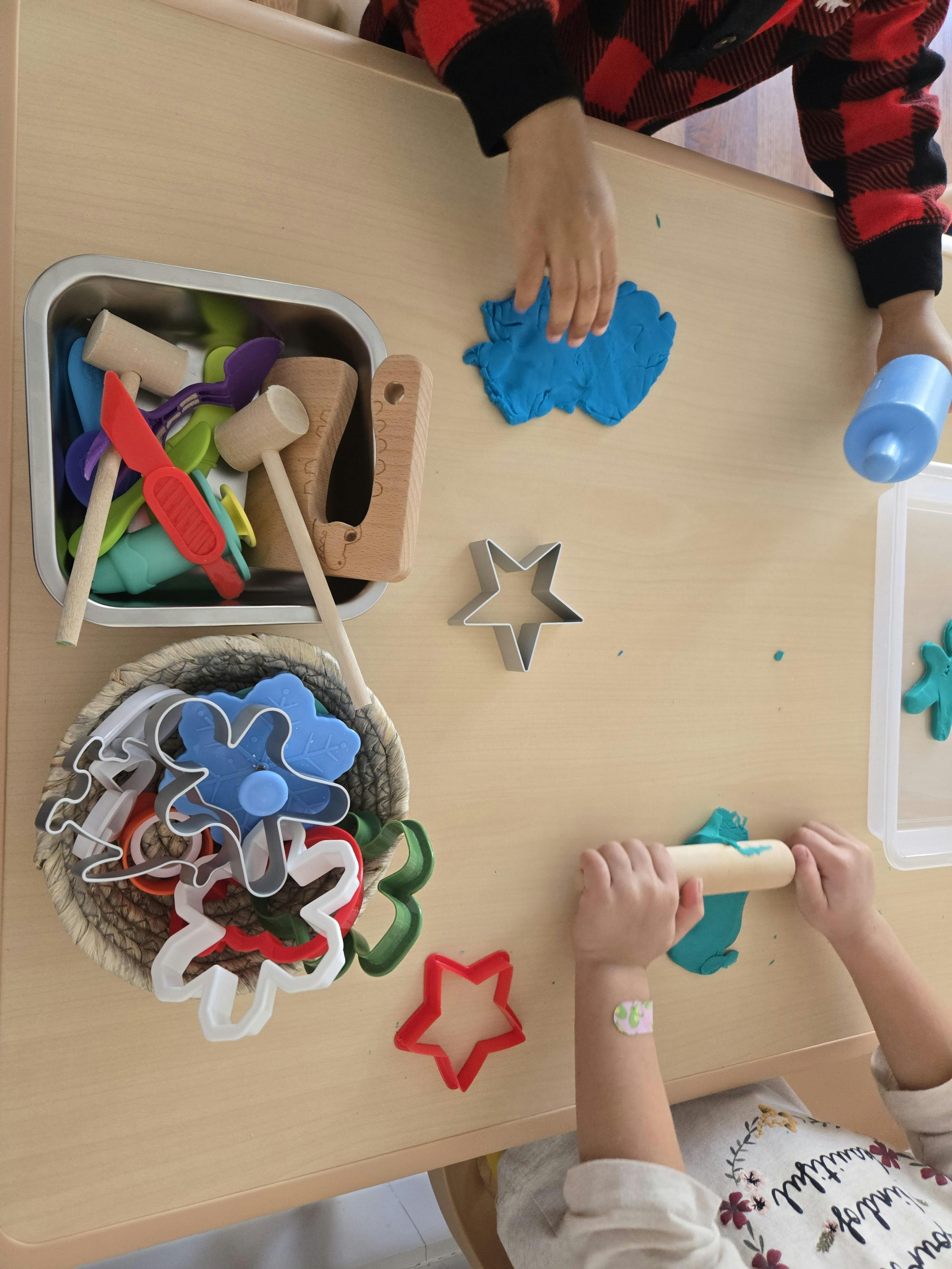 Children playing with blue playdough and cookie cutters at a table