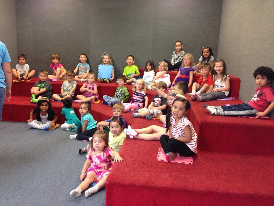 Group of children sitting on red tiered seating