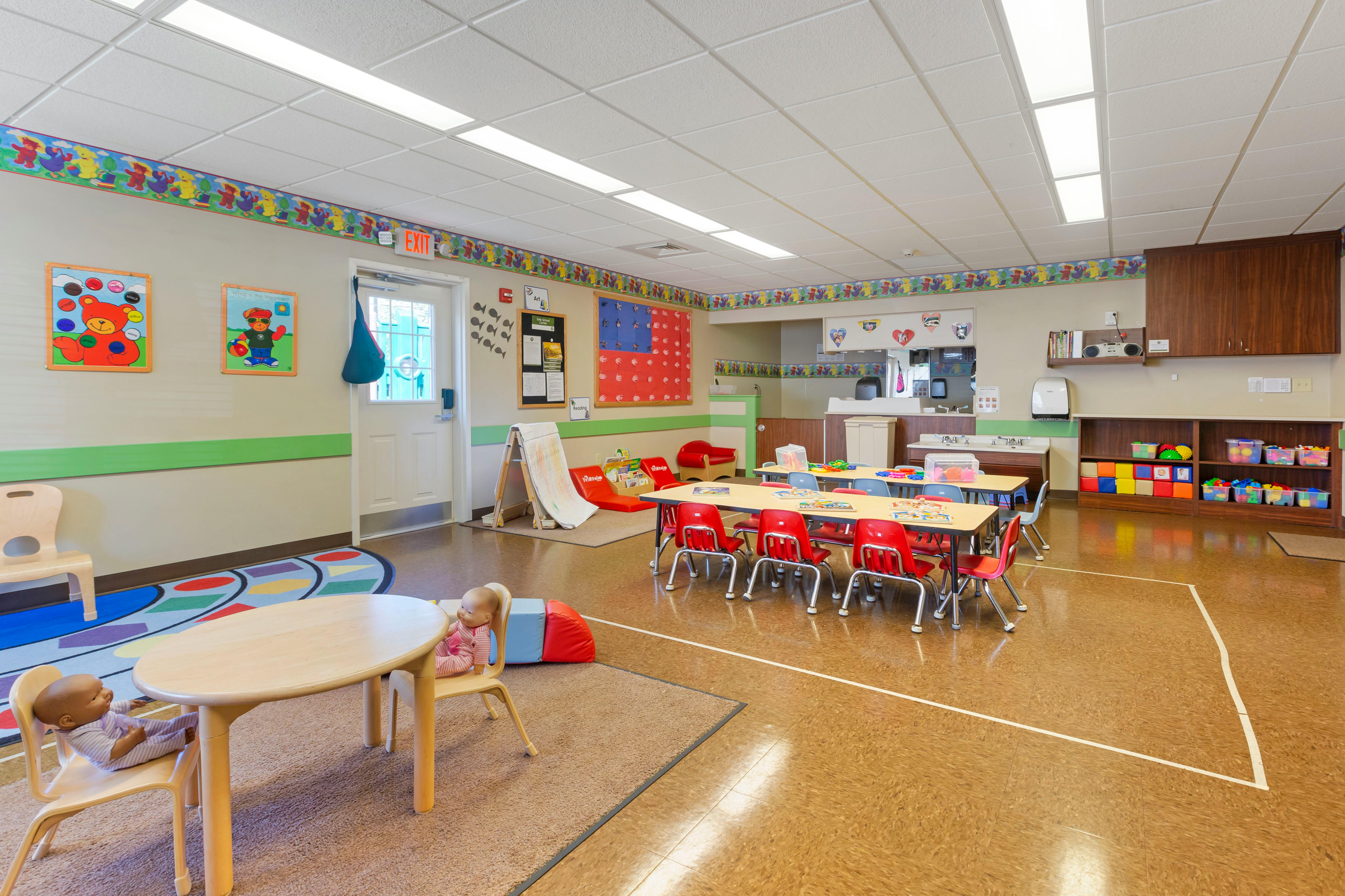 Classroom with child-sized tables and chairs, educational posters, and toys
