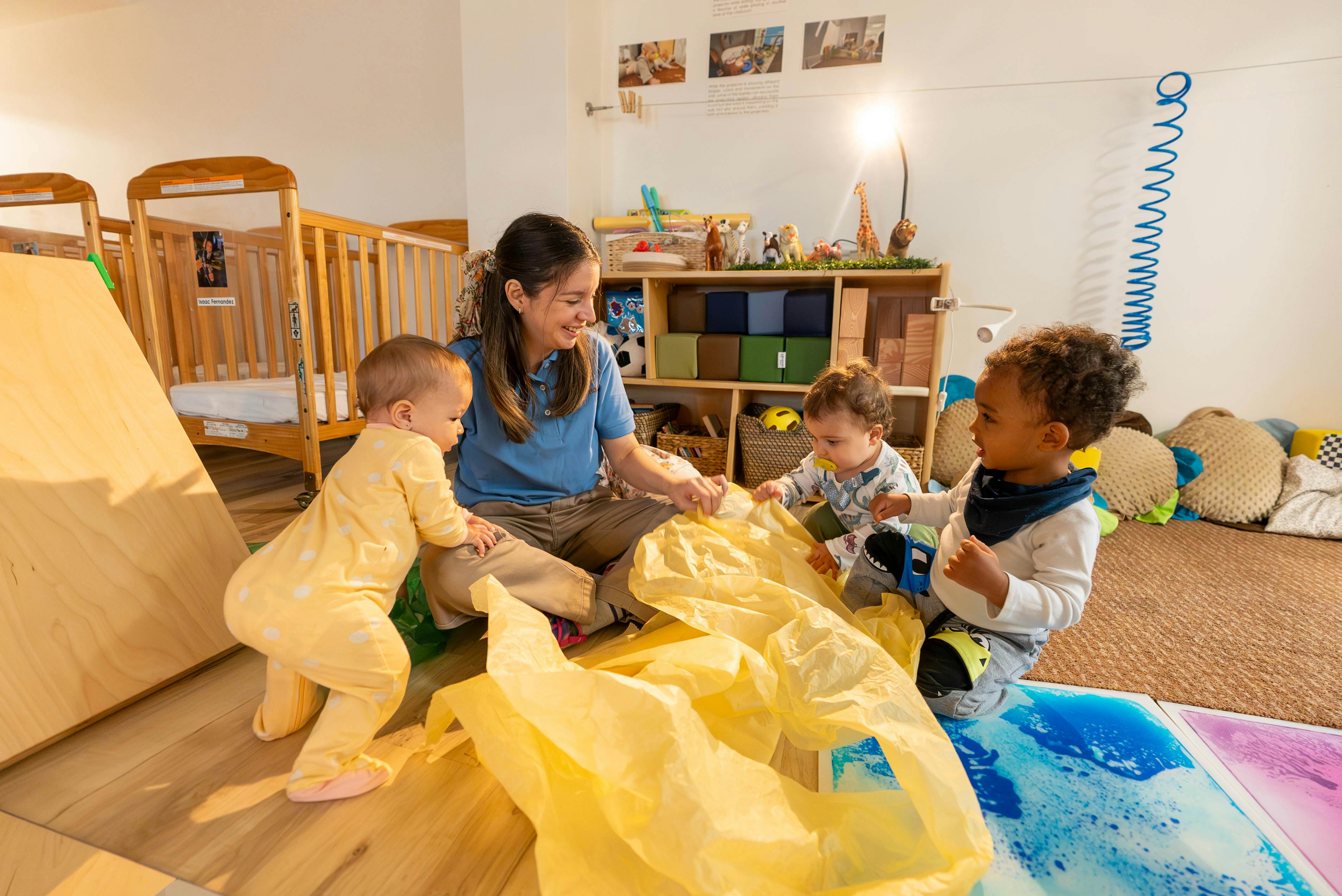 Adult and three children playing with crinkly yellow plastic on the floor
