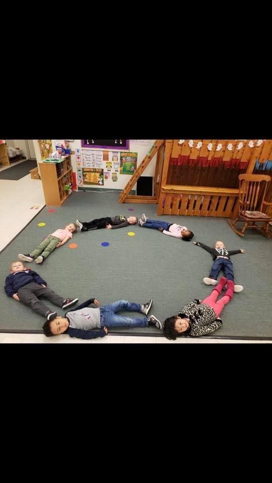 Children lying on the floor in a circle in a classroom