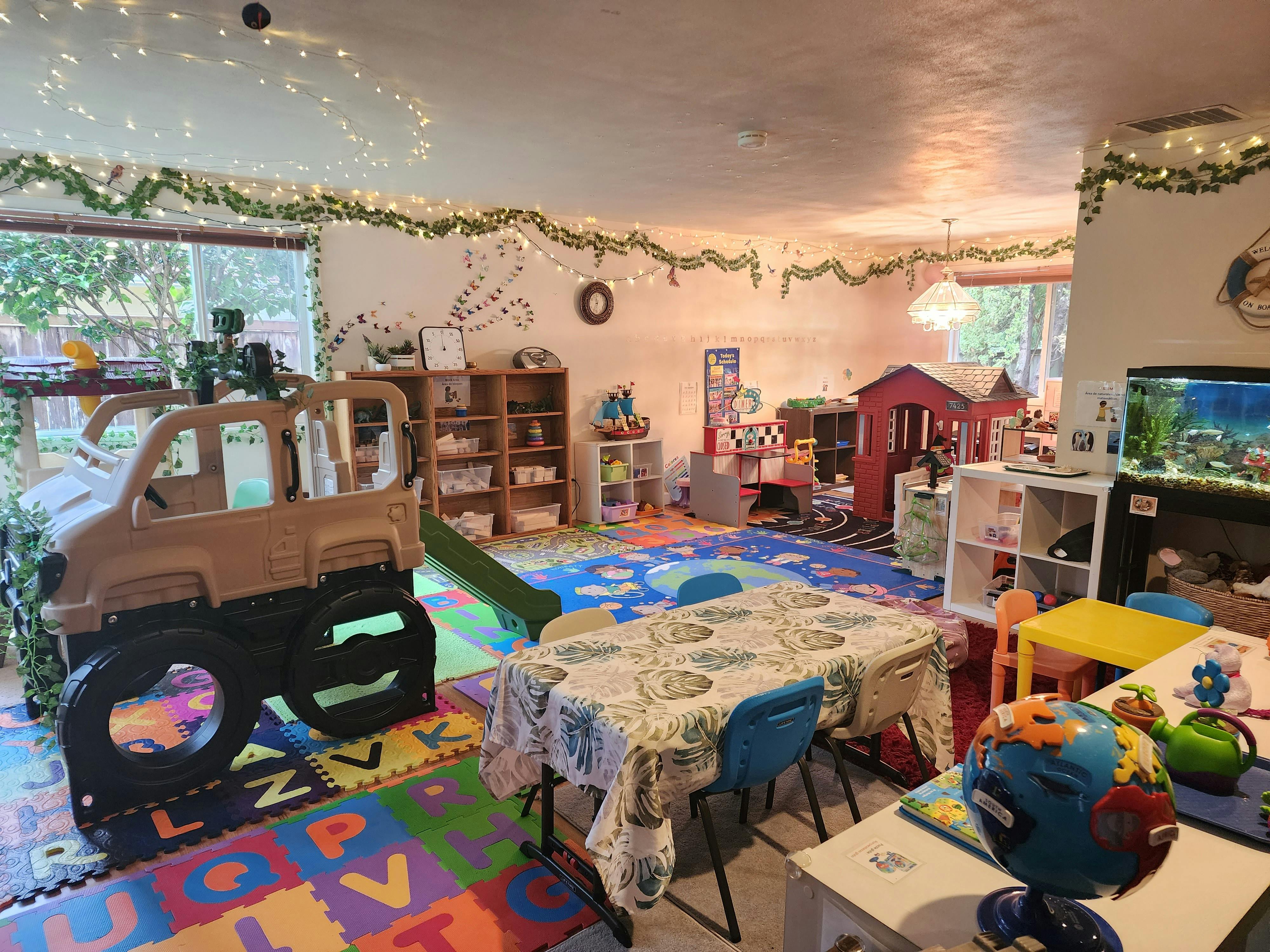 Playroom with a toy car, tables, and playhouses