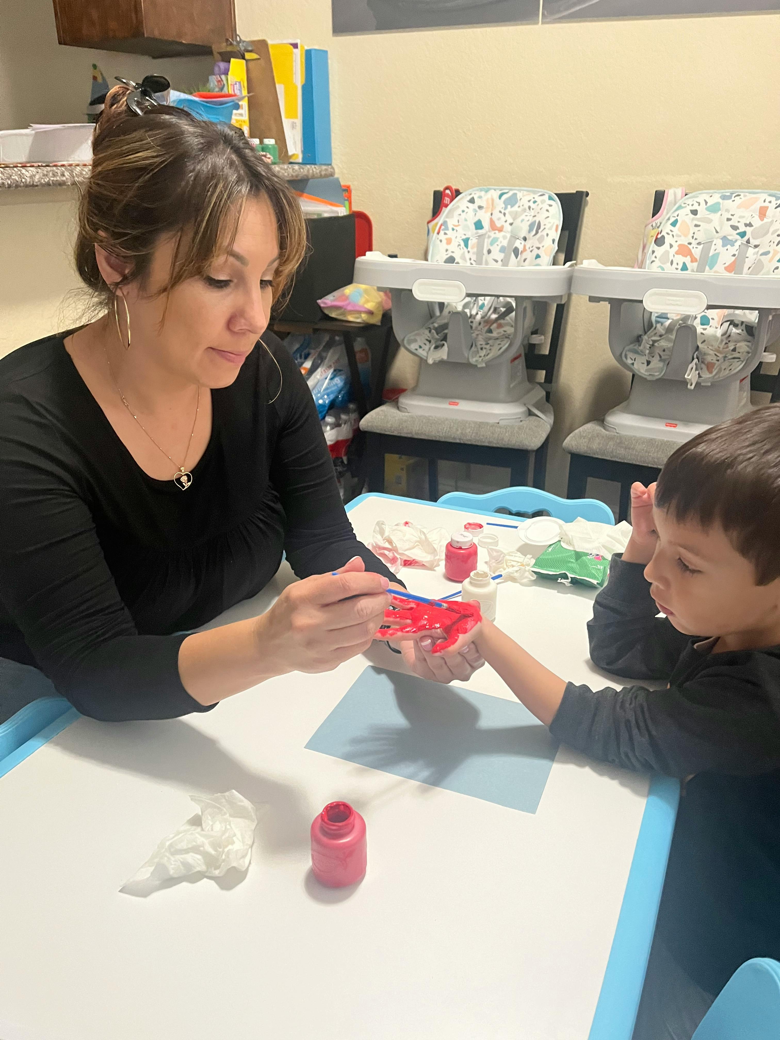 Person helping a child paint a craft