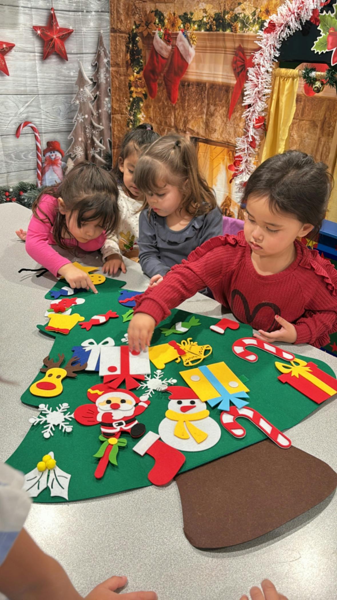 Children decorating a felt Christmas tree with ornaments