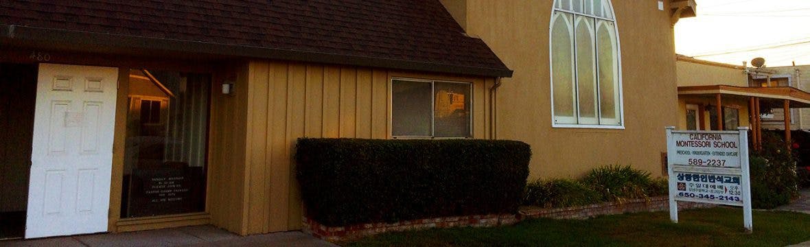 Building exterior with a white door, windows, and a sign in the foreground