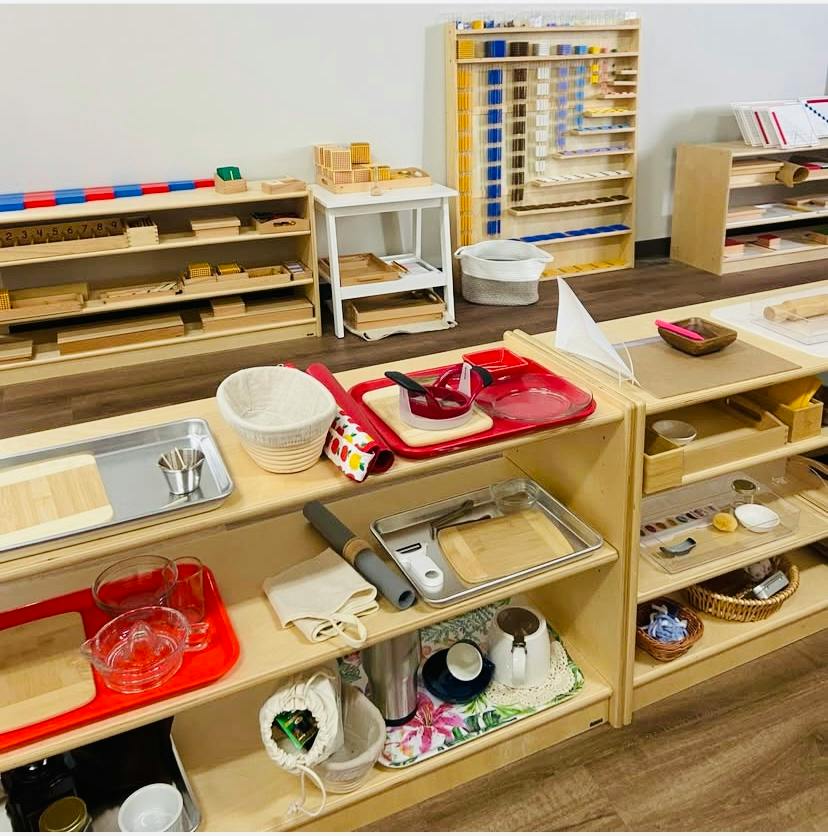 Wooden shelves with trays containing kitchen tools and educational materials