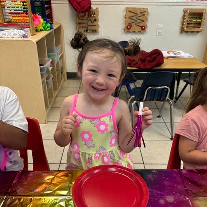 Child holding a small party blower in a classroom