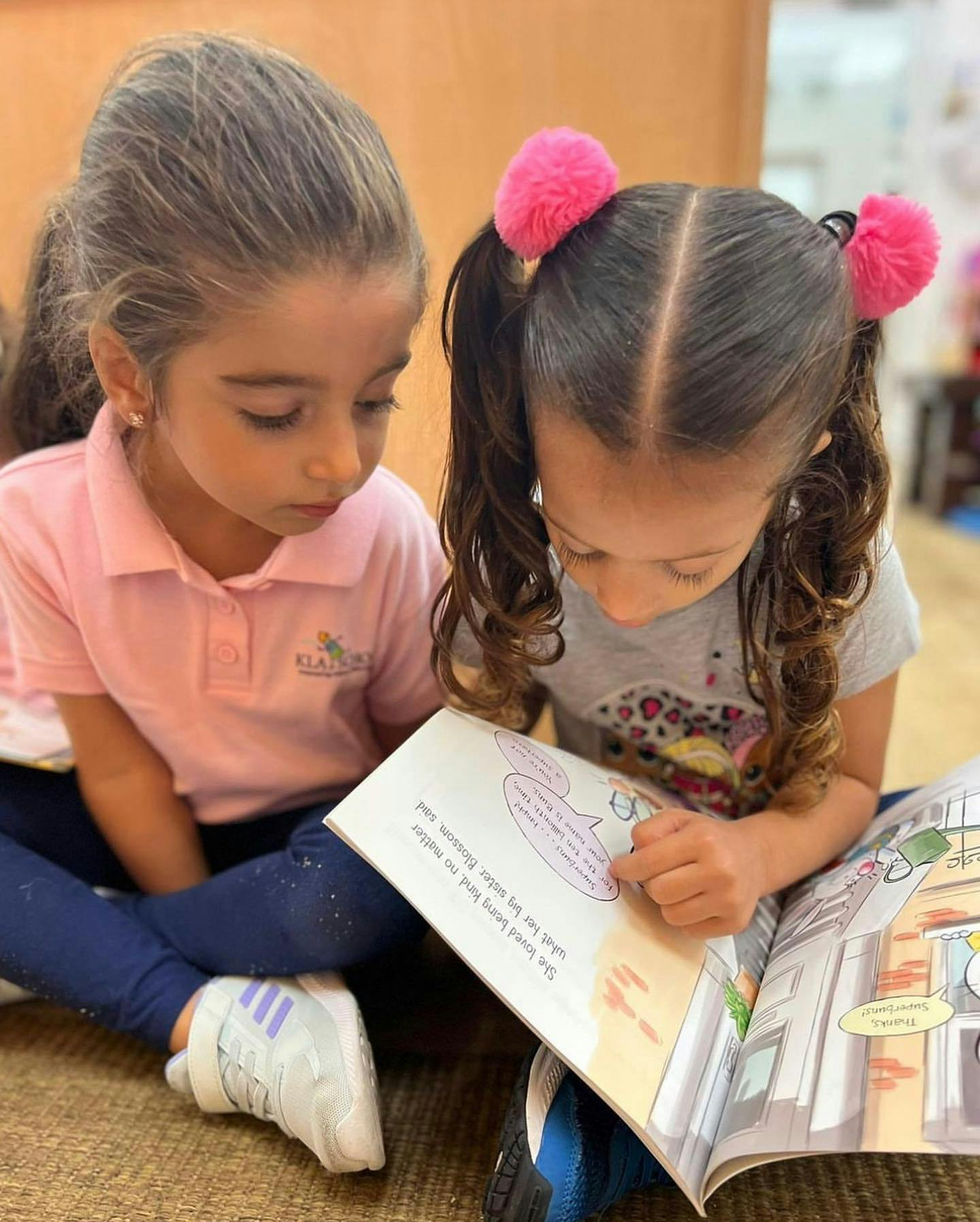 Two children sitting on the floor reading a book together