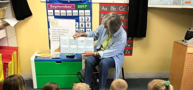 Person reading a book to children in a classroom