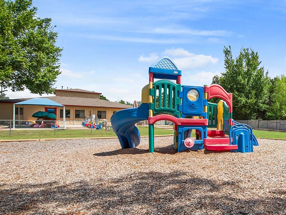 Colorful playground structure with slides on wood chip ground