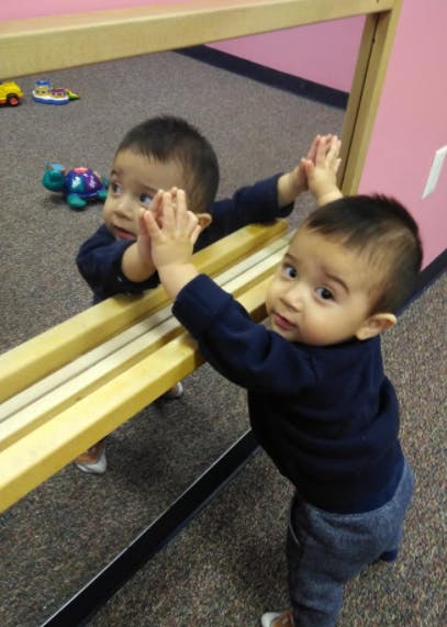 Child standing and looking at their reflection in a mirror