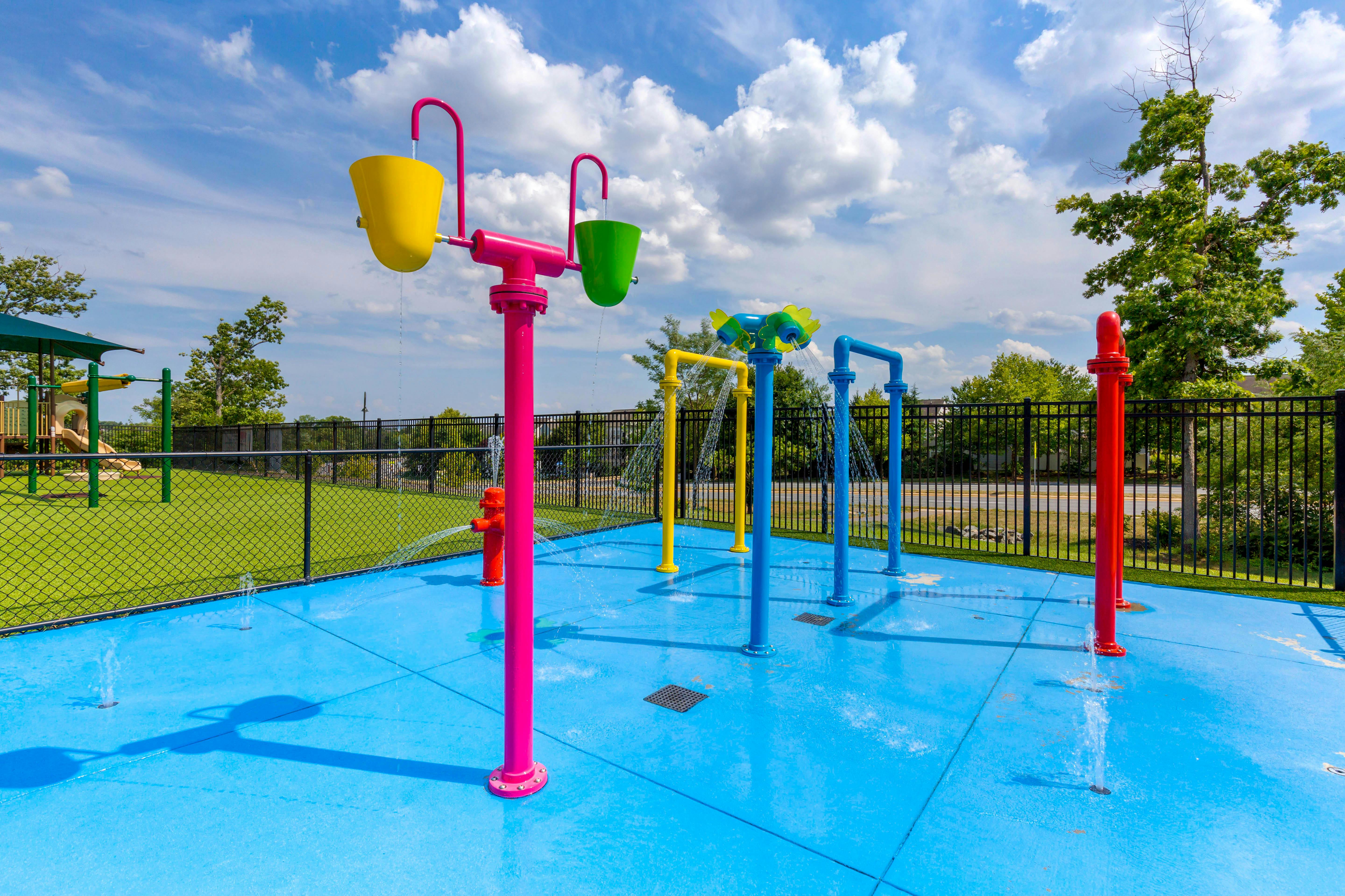 Colorful water features with spraying water on a bright blue splash pad