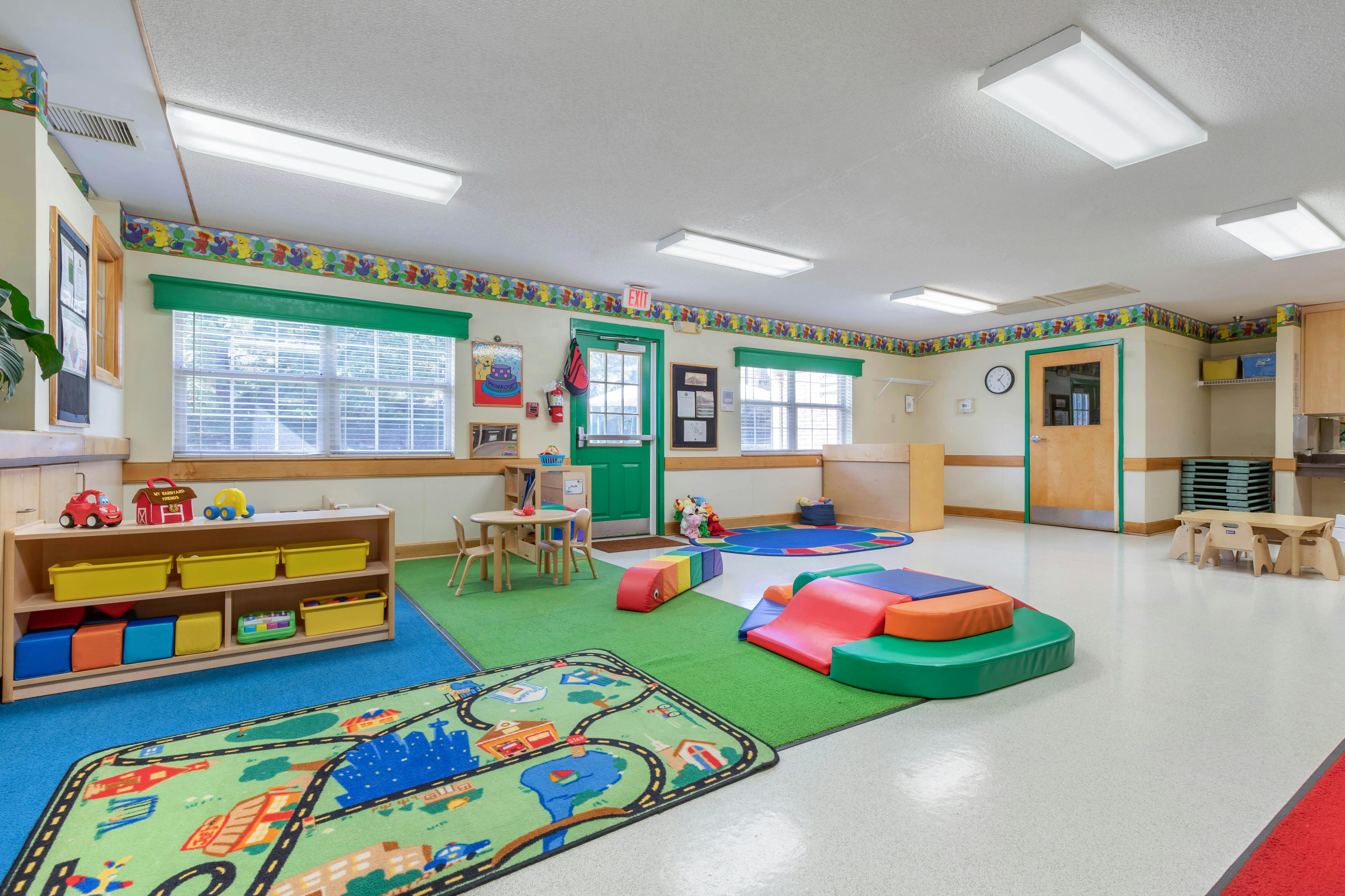 Playroom with small tables, play mats, and a toy shelf