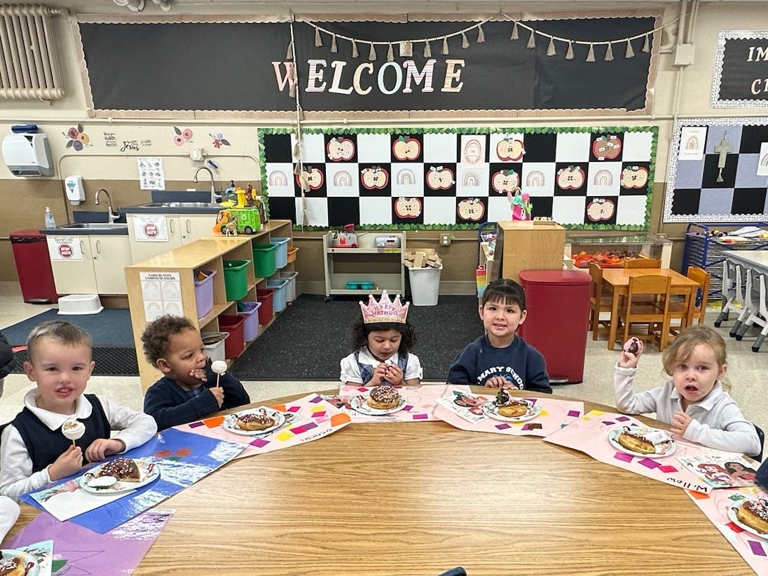 Children eating treats at a round table in a classroom