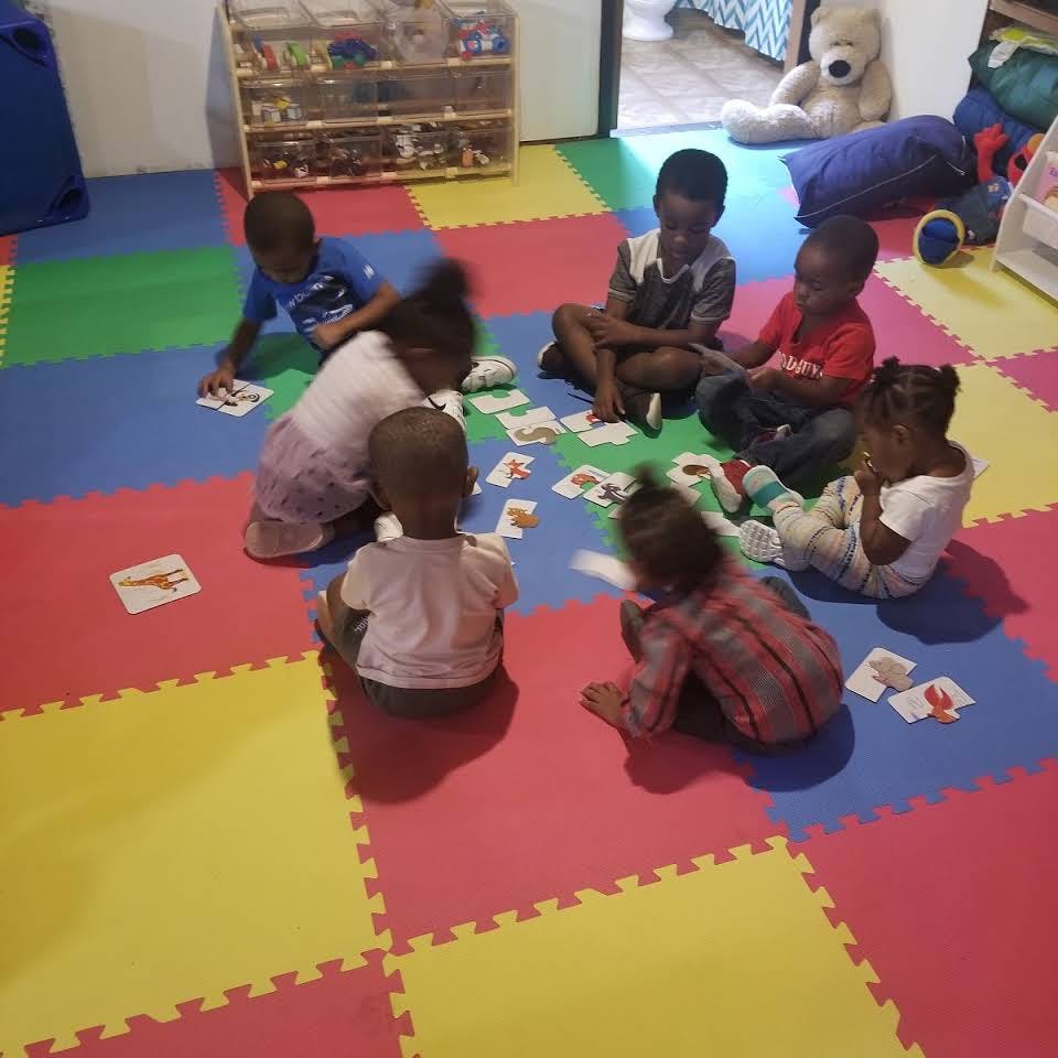 Group of children sitting on a colorful mat playing with cards