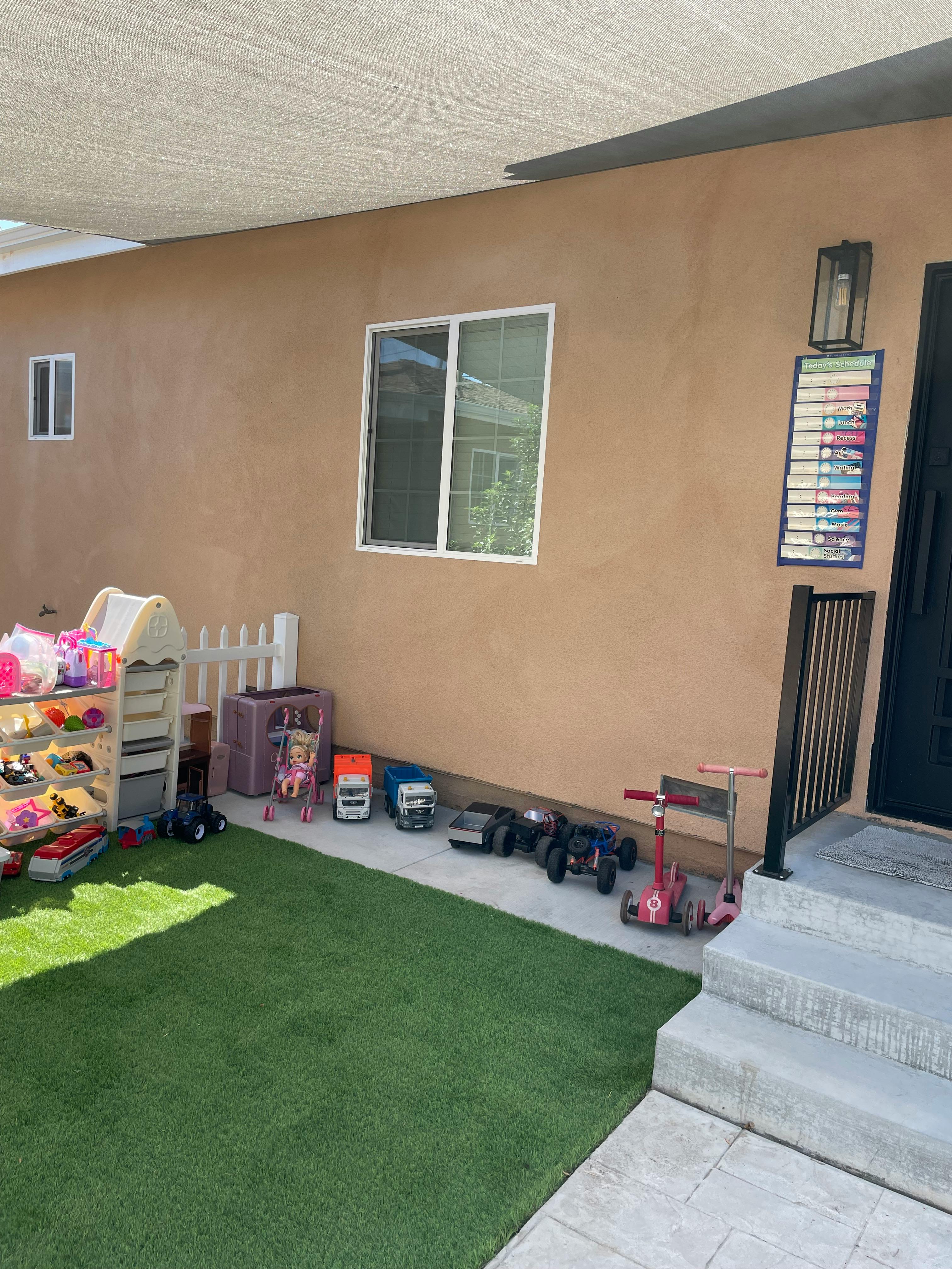 Outdoor play area with artificial turf, toys, and a small fence