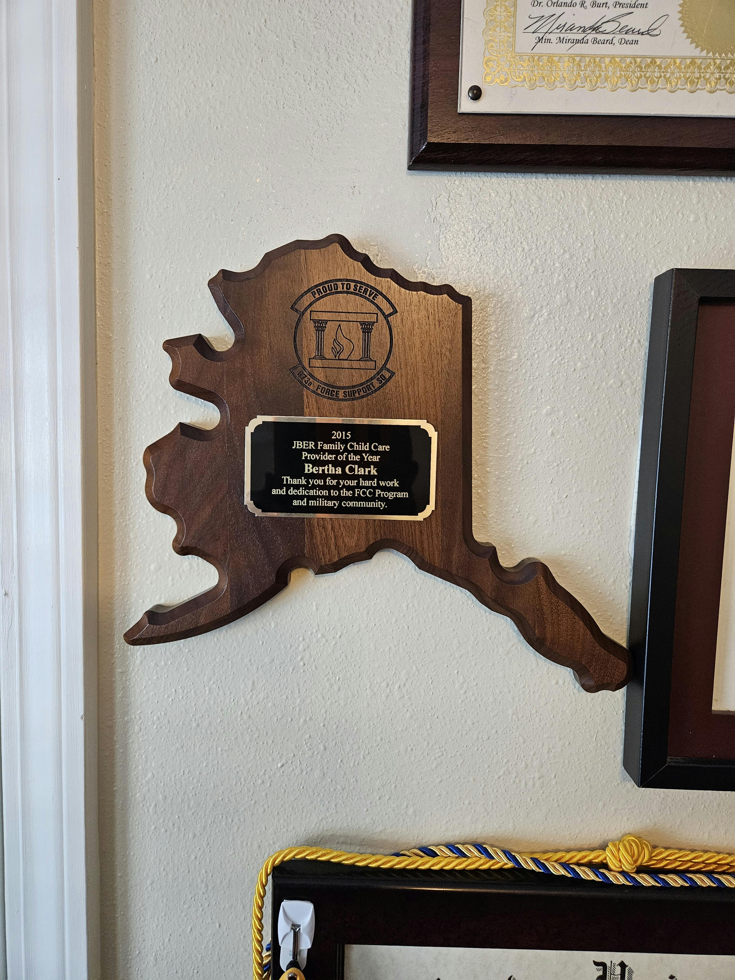Wooden plaque shaped like Alaska with an engraved metal plate