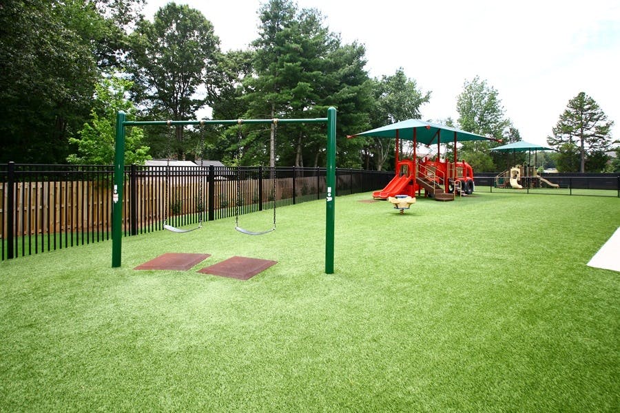 Playground with swings and a play structure on artificial turf