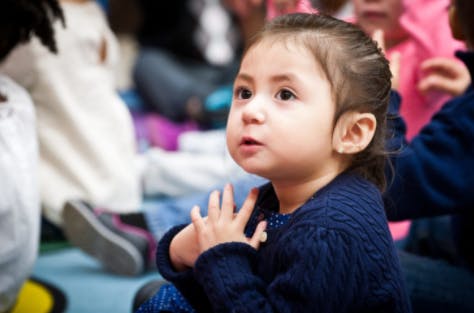 Child looking up with hands clasped