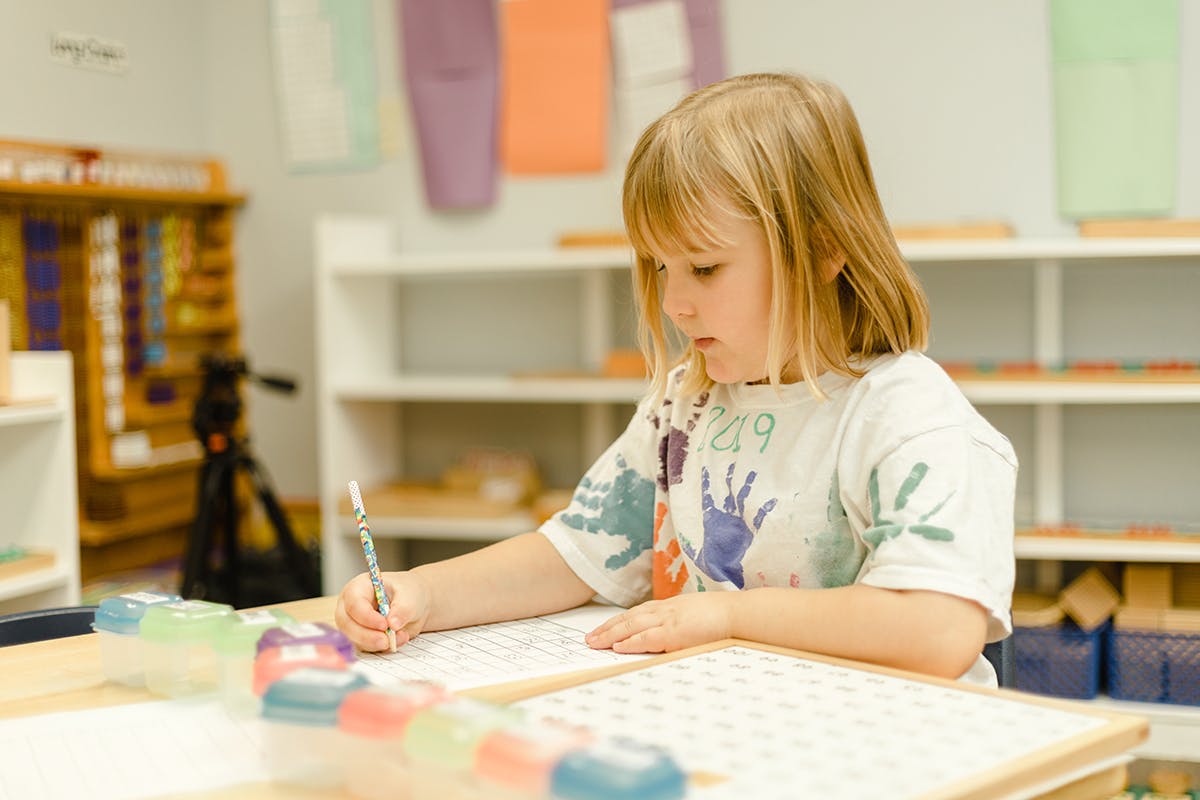 Child writing at a desk in a classroom