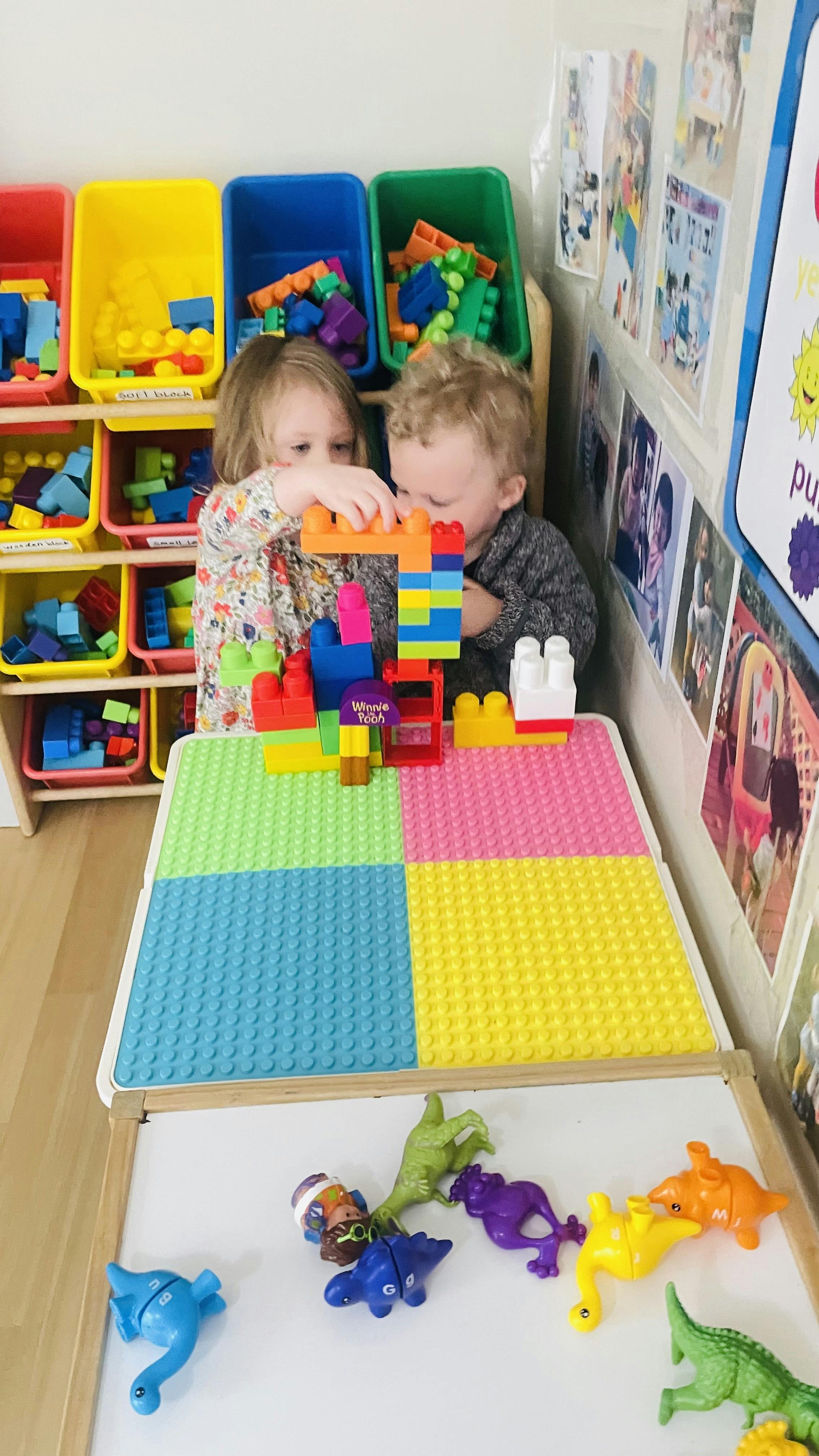 Two children playing with colorful building blocks at a table