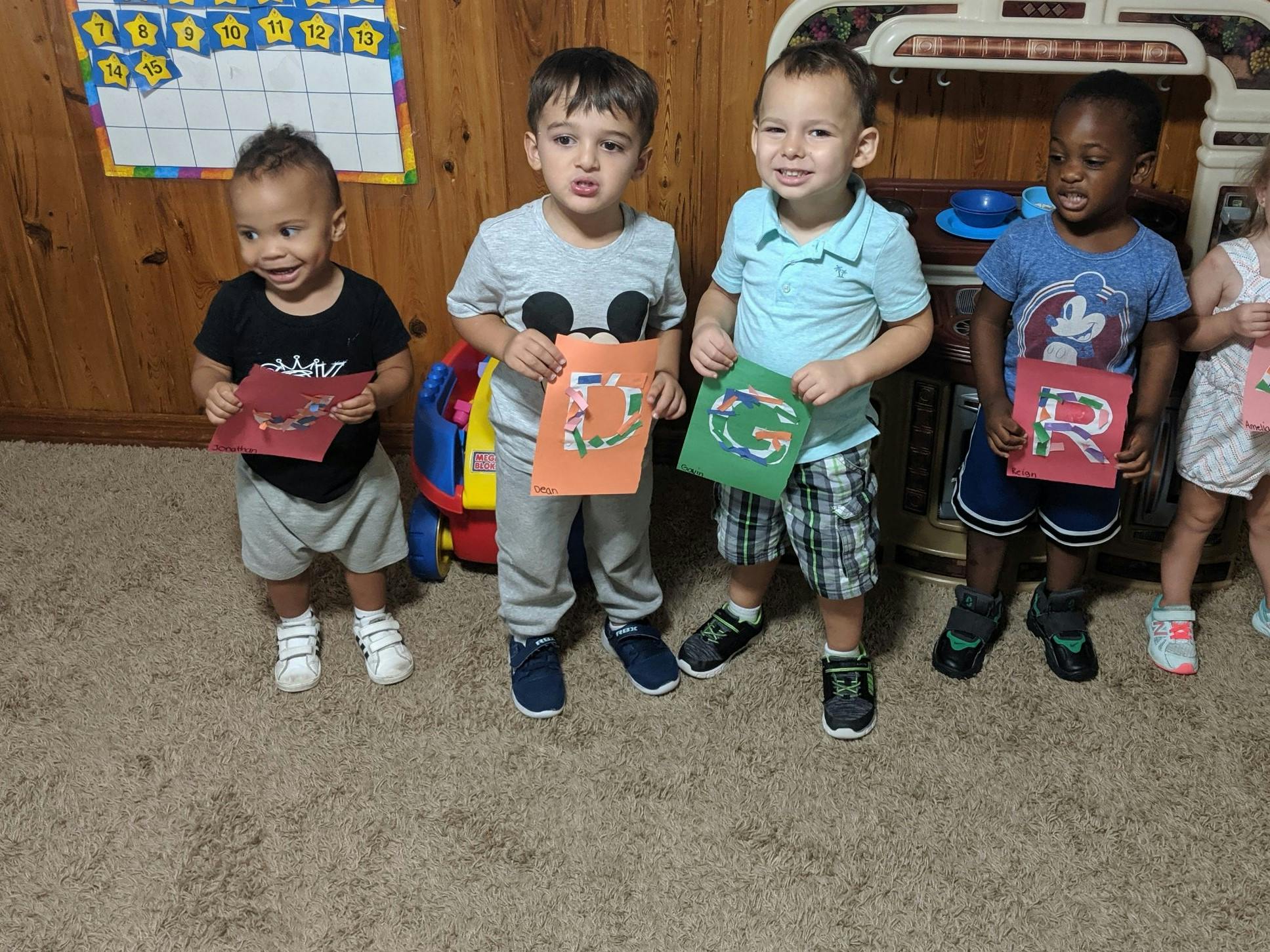 Four children holding up colorful papers with letters on them