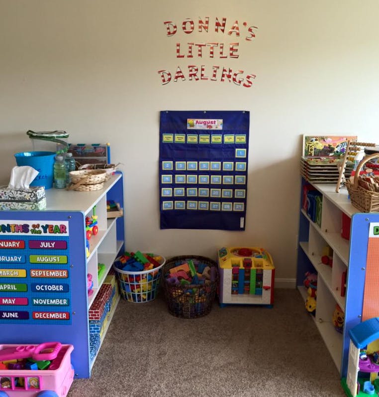 Playroom with shelves of toys, calendar, and "Donna's Little Darlings" on wall