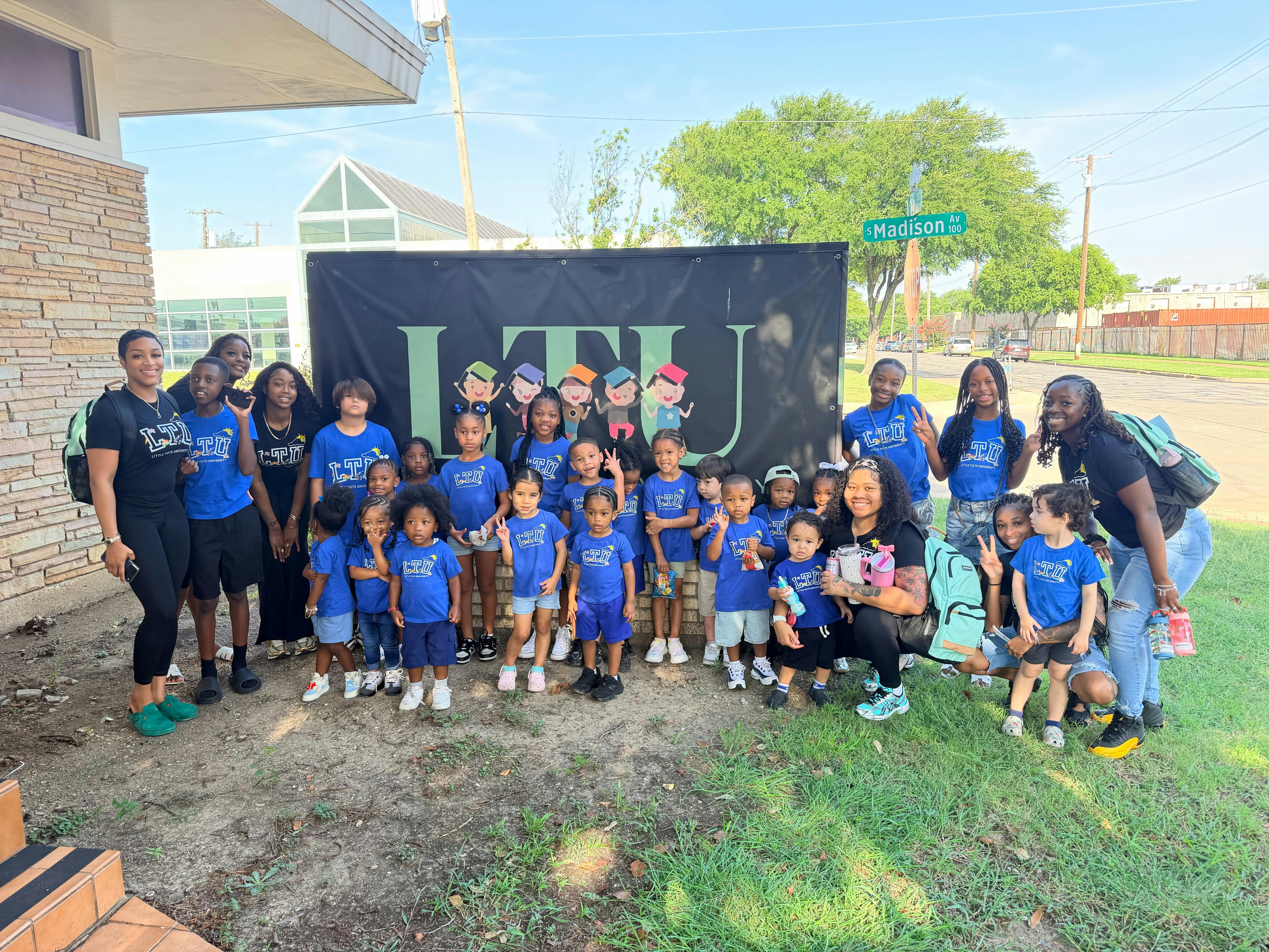 Group of children and adults wearing matching blue shirts posing in front of LTU