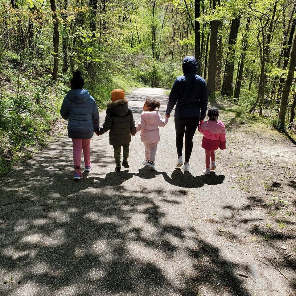 Person and three children walking on a path in a wooded area