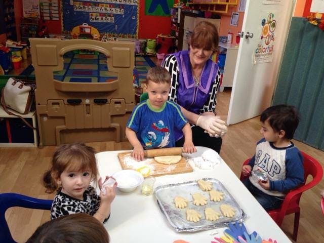 Adult and children making cookies in a classroom