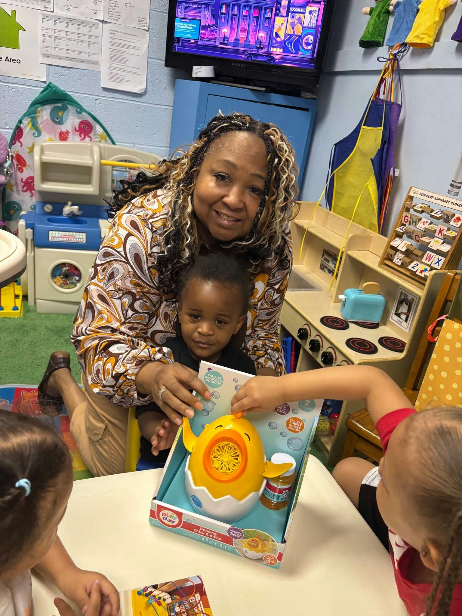 Adult and children playing with a bubble toy in a classroom